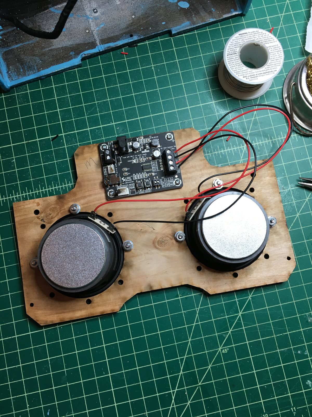 The Raspberry Pi and amplifier wired to two speakers on a mounting board