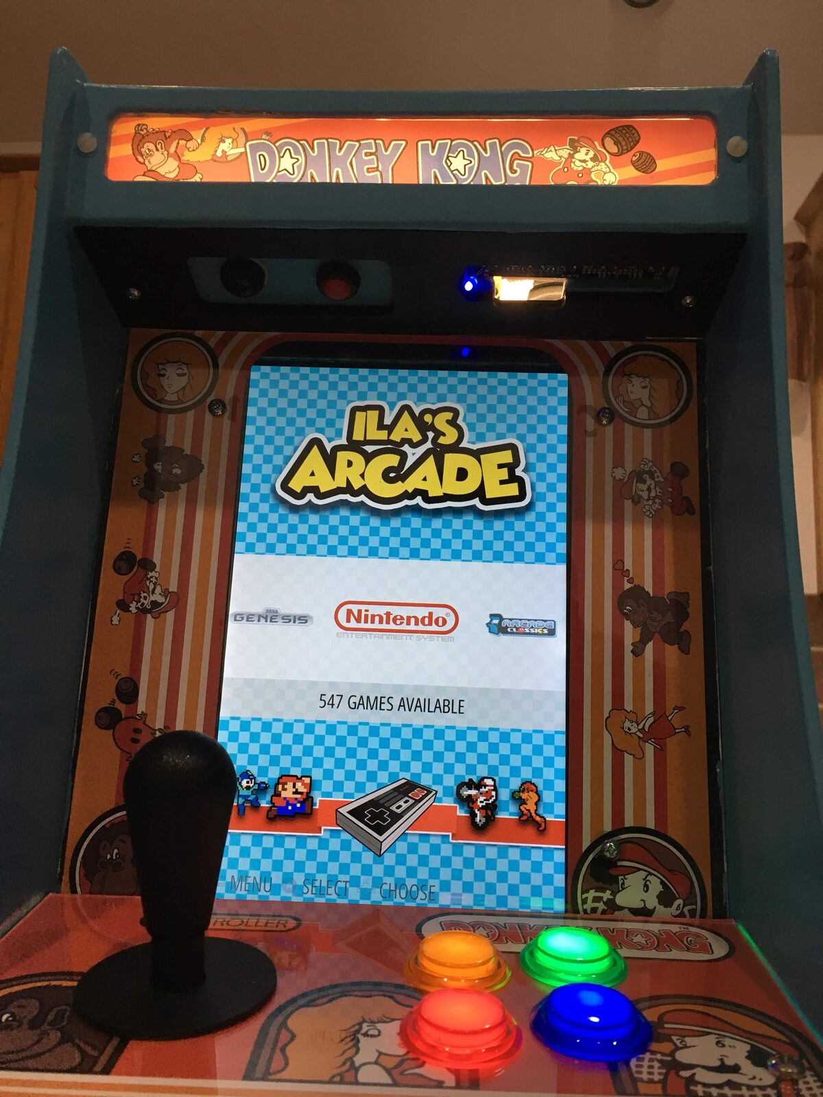 The finished bartop arcade lit up, custom marquee and RGB buttons, a game menu on screen