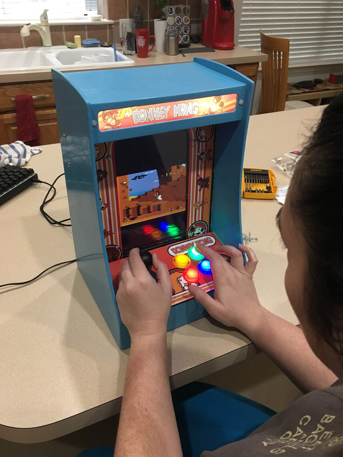 Playing the finished arcade, hands on the lit buttons and stick