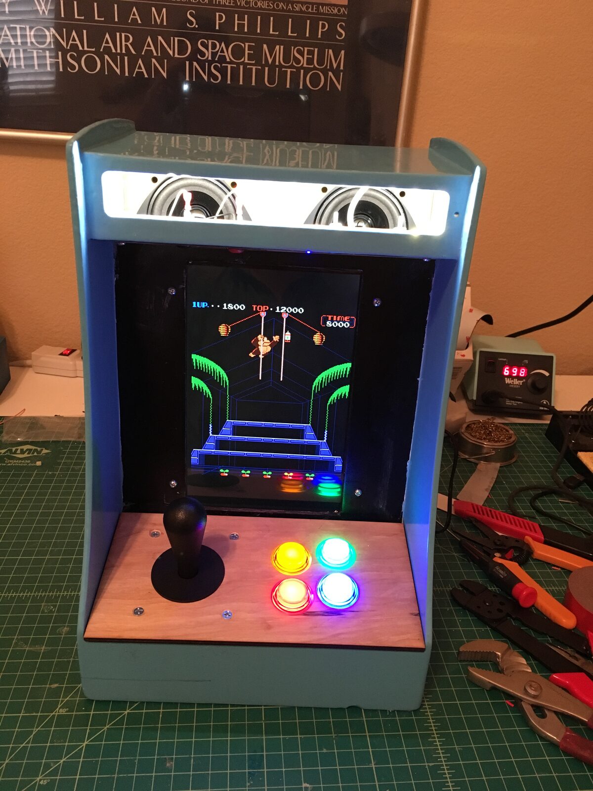 The cabinet powered on in a dark room, buttons and marquee glowing